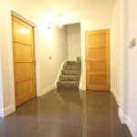 Modern hallway with wooden doors and carpeted stairs.