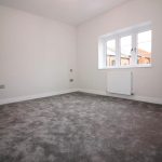 Empty carpeted room with window and radiator