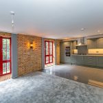 Modern kitchen with green cabinets and brick walls.
