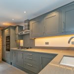 Modern kitchen with grey cabinets and brick wall