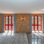 Modern room with red-framed windows and brick wall.