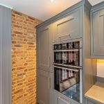 Modern kitchen with brick wall and double oven.