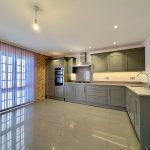 Modern kitchen with grey cabinets and brick wall.