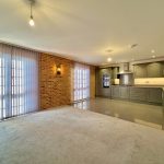 Spacious open-plan kitchen and living area with brick wall.