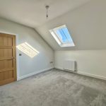 Bright room with skylight and wooden door.