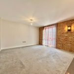 Spacious living room with brick wall and natural light.