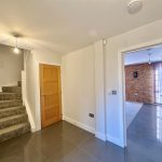 Modern hallway with stairs and open door.
