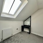 Modern attic room with skylight and dressing table.