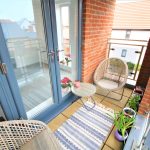 Cosy balcony with chairs, rug, and plants.