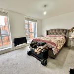 Bright bedroom with double bed and large windows.