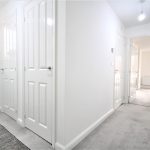Bright hallway with white doors and carpet.