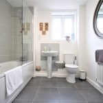 Modern bathroom with tiled bathtub and round mirror.