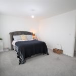Modern bedroom with double bed and grey carpet.