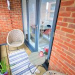 Cosy balcony with wicker chairs and potted plants.