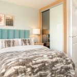 Cosy bedroom with teal headboard and fur blanket.