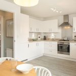 Modern white kitchen with appliances and dining area.