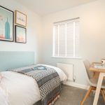 Cosy bedroom with desk and decorative wall art.