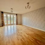Spacious room with wooden floor and patio doors.