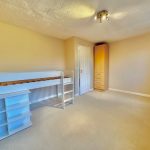 Empty beige room with loft bed and wardrobe.