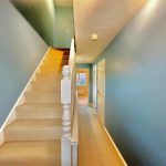 Blue hallway with staircase and ceiling light.