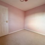 Empty pink-walled room with a closed door.