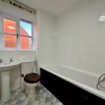 Modern white bathroom with bathtub and window.