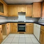 Modern kitchen with wooden cabinets and tiled floor.