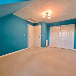Empty blue room with beige carpet and white doors.
