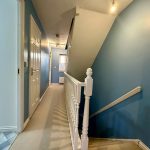 Blue painted hallway with staircase and doors.