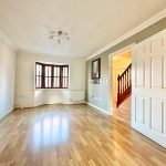 Spacious living room with wooden flooring and large window.