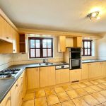 Modern kitchen with wooden cabinets and tiled floor.