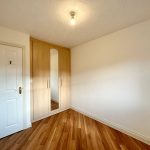 Minimalist bedroom with wooden floor and wardrobe.