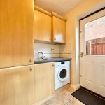 Utility room with washing machine and wooden cabinets.