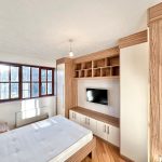 Modern bedroom with wooden furniture and large window.