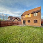 Spacious garden with brick house and fencing.