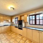 Spacious modern kitchen with wooden cabinets and windows.