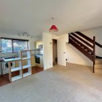 Bright, open-plan living room with staircase and kitchen.