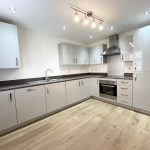 Modern grey kitchen with wooden flooring.