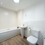 Modern white bathroom with bathtub and wooden floor.