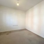 Empty white room with single light bulb.
