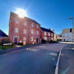 Residential street with red brick houses, sunny day.