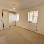 Empty beige bedroom with carpet and window blinds.