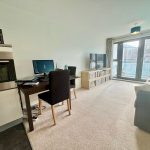 Modern living area with desk and large windows.