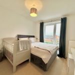 Cosy bedroom with cot, window view, bright lighting.