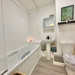 Modern bathroom with white tiles and fixtures.