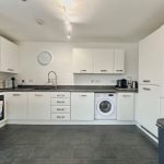 Modern kitchen with white cabinets and appliances.