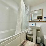 Modern bathroom with bathtub and white tiles.