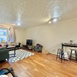 Spacious living room with wooden floor and TV.