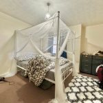 Bedroom with canopy bed and patterned rug.