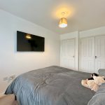 Cosy bedroom with TV, double doors, and lighting.